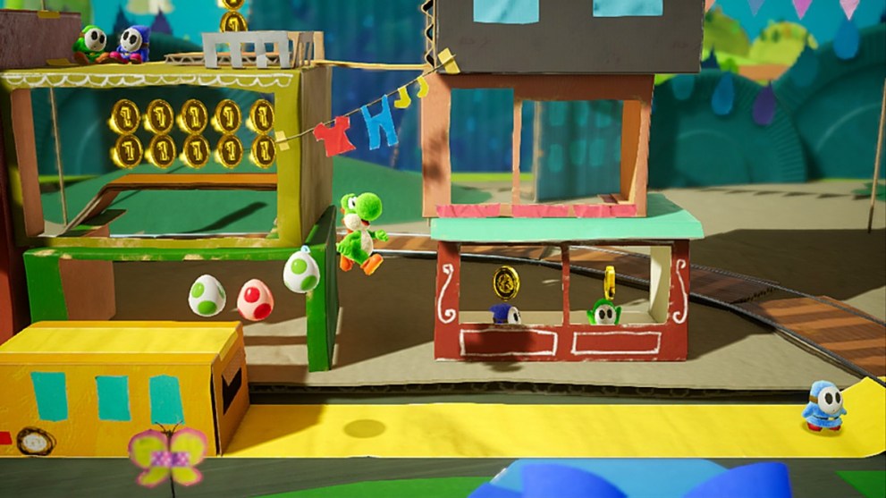 Yoshi, Nintendo's green dinosaur character, jumps from a cardboard platform - followed by a trail of spotted eggs.  The world itself is crafted from paper, and appears to be in the shape of a shop stall run by Shy Guys.