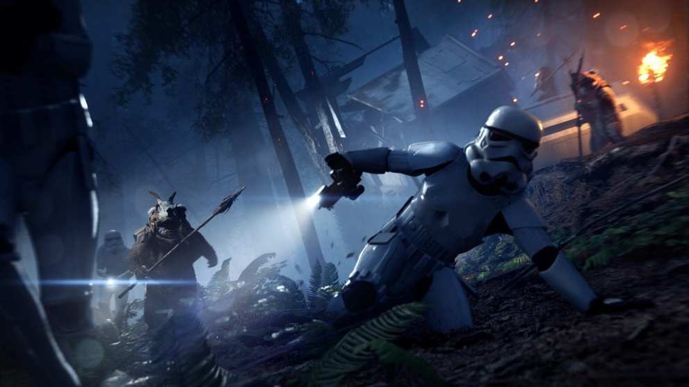 An ewok, a small bear-like creature from the Star Wars franchise, runs through a wooded area with burning wreckage around them.  They are chasing after a retreating Stormtrooper - the infantry of te galactic empire.   