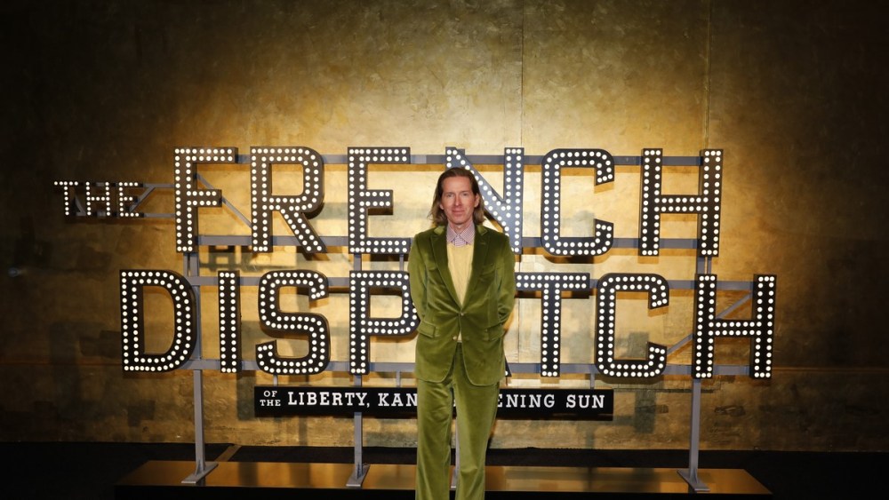 Wes Anderson standing in front of a Sign for The French Dispatch
