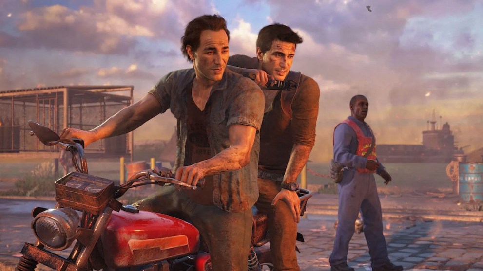 A middle-aged Nathan Drake, protagonist of the Uncharted video game series, sits on the back of a dirty motorbike. He leans against his older brother's back while they watch a sunset off-frame.