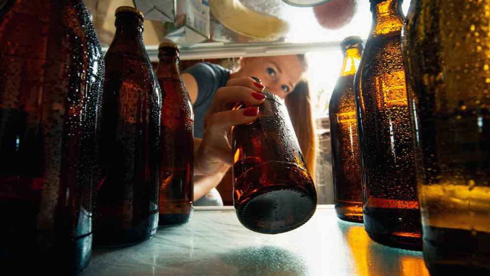 Woman grabbing beer from fridge