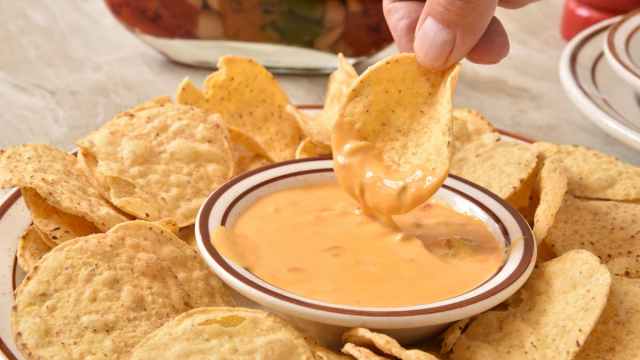 Dipping tortilla chip in cheese sauce