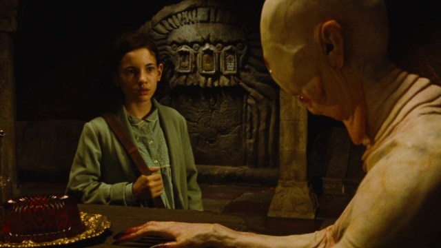 A young girl confronting a pale monster who's sitting at a dinner table with missing eyes and sharp bloody claws.