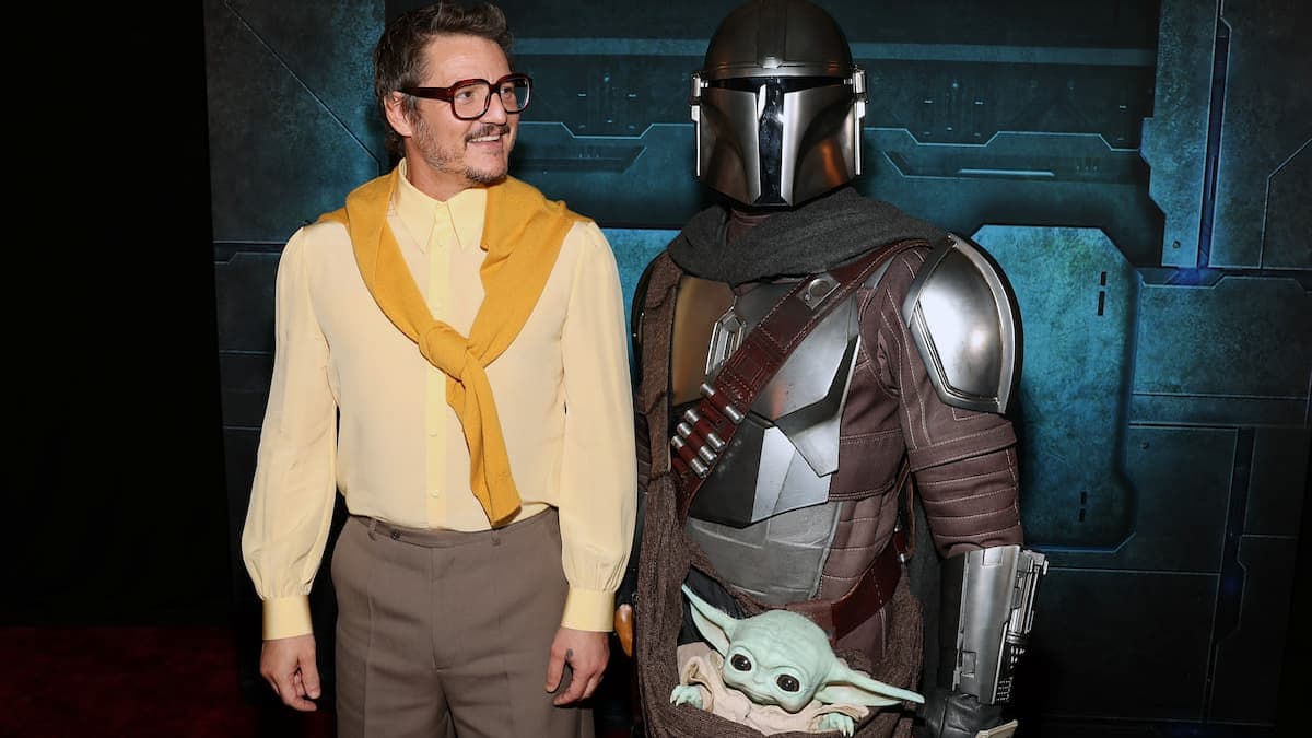 Pedro Pascal stands with the Mandalorian and Grogu