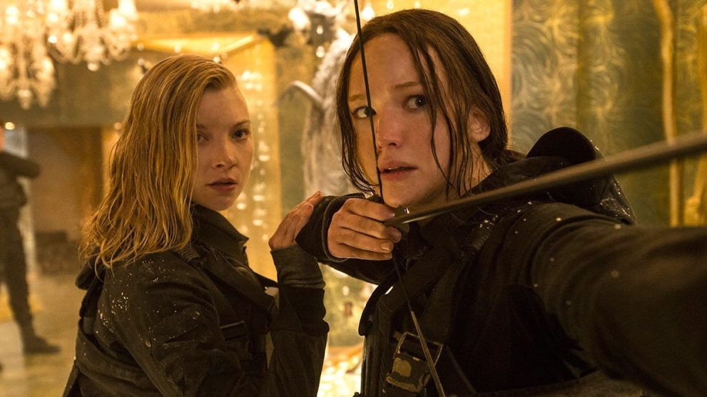 Katniss Everdeen (Jennifer Lawrence) shooting an arrow, next to Cressida (Natalie Dormer) in The Hunger Games: Mockingjay - Part 2.