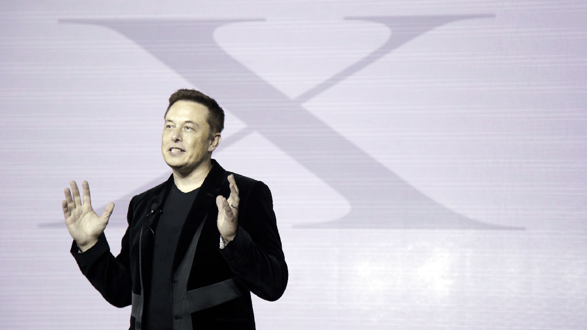 Elon Musk standing in front of X logo